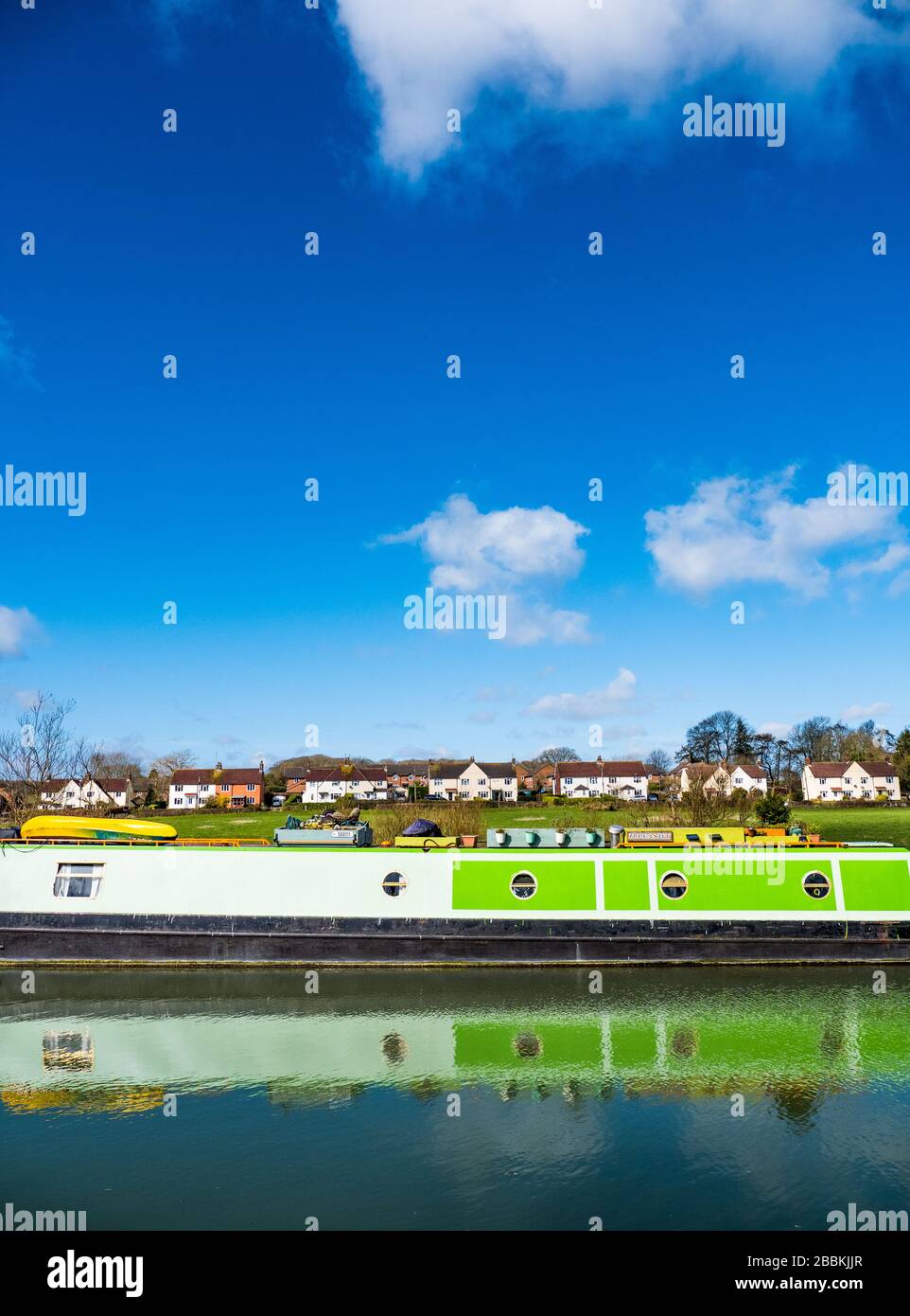 Grünes Narrowboat spiegelt sich auf dem Kennet und Avon Canal, Great Bedwyn, North Wessex Downs, Wiltshire, England, Großbritannien, GB. Stockfoto