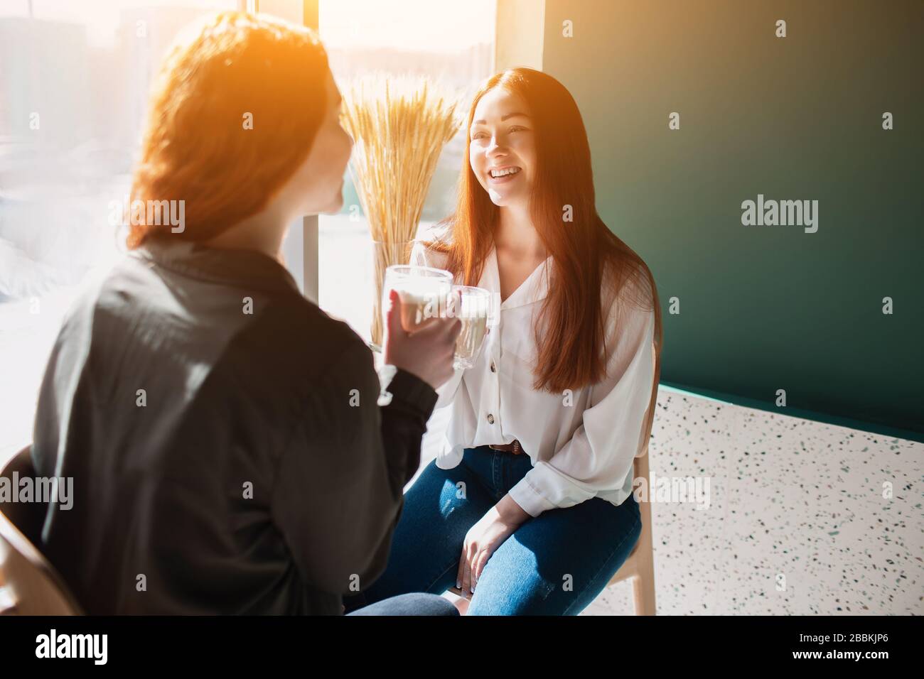 Rothaarige zwei junge Frauen sprechen und trinken Kaffee. Weibliche Modelle lauern in einem Café Stockfoto