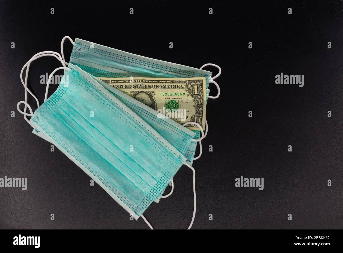 Gesichtsmasken und Banknoten von 1 Dollar auf schwarzem Hintergrund. Das Konzept des Mangels, der Spekulation und des Mangels an medizinischen Masken im Verkauf. Stockfoto