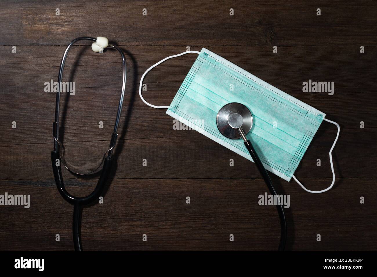Medizinische Einwegmaske, Stethoskop auf Holzhintergrund. Das Konzept des Schutzes während einer Epidemie der Krankheit. Stockfoto