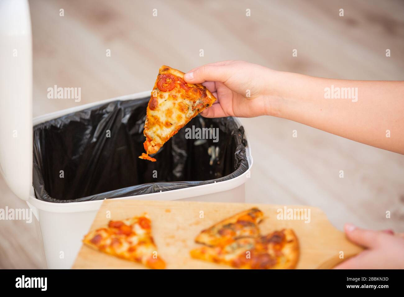 Verschwenden Sie keine Lebensmittel mehr, geben Sie der Frau etwas Essen, Pizza in die Mülltonne, Müll, Essenskonzept Stockfoto