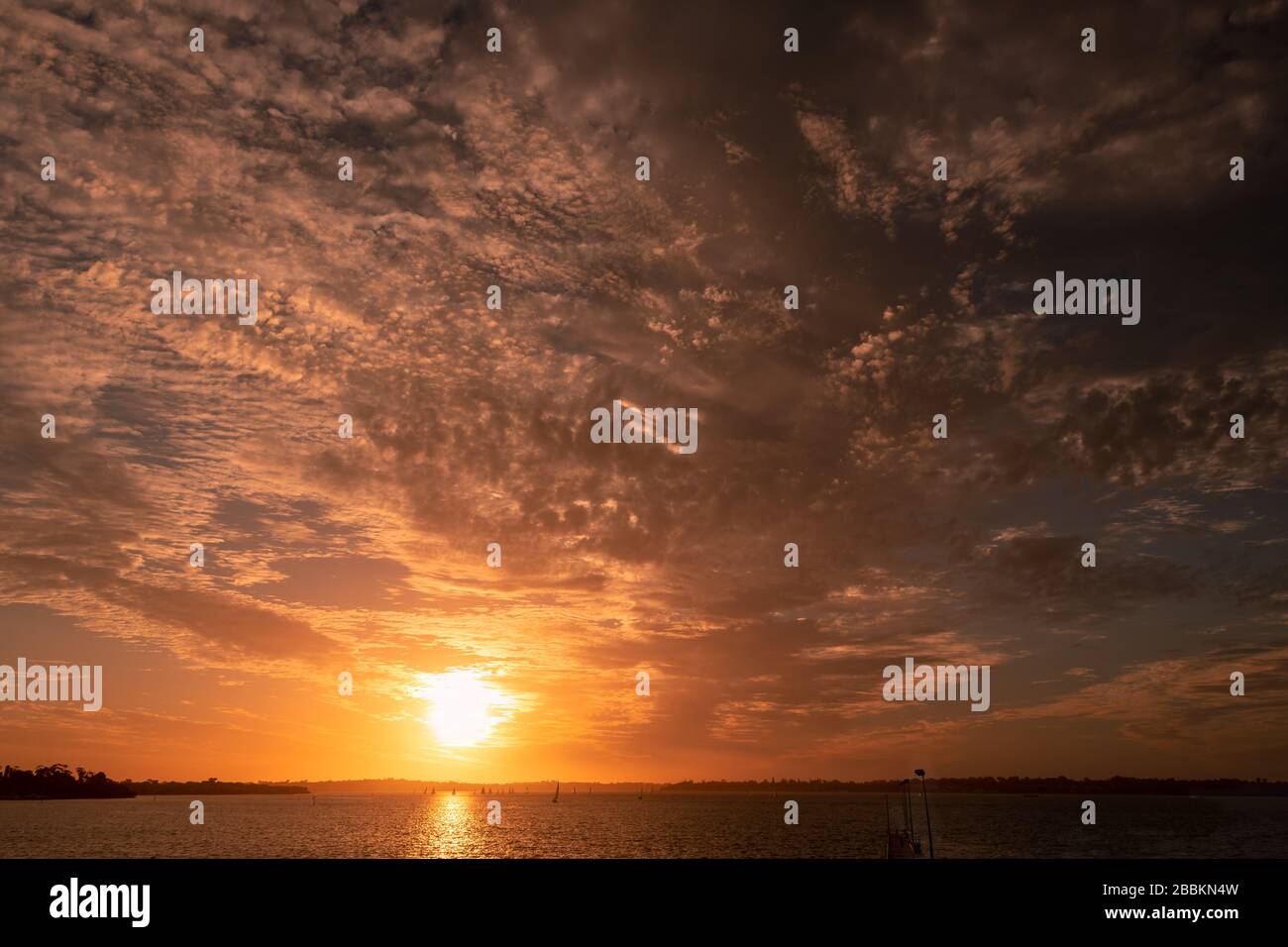 Feuriger Sonnenuntergang über dem Swan River, Perth West Australia. Idyllische Szene mit Segelbooten beim Dämmersegeln Stockfoto