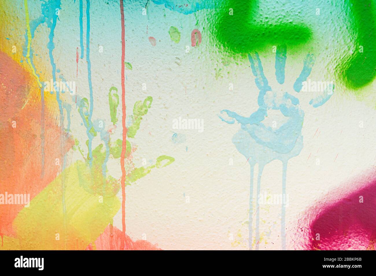 Weiß verputzte Wand mit bunten Tropfen, Strömen und Lacksprays. Handdrucke auf weißem Wandhintergrund Stockfoto