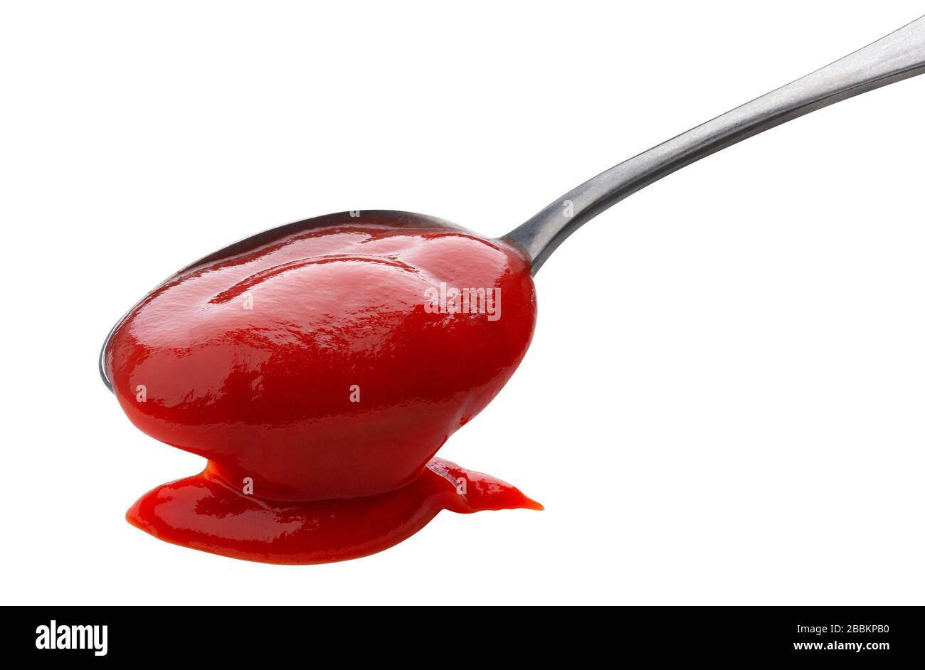 Fließendes Ketchup isoliert auf weißem Hintergrund, Tomatensauce mit Metalllöffel Stockfoto