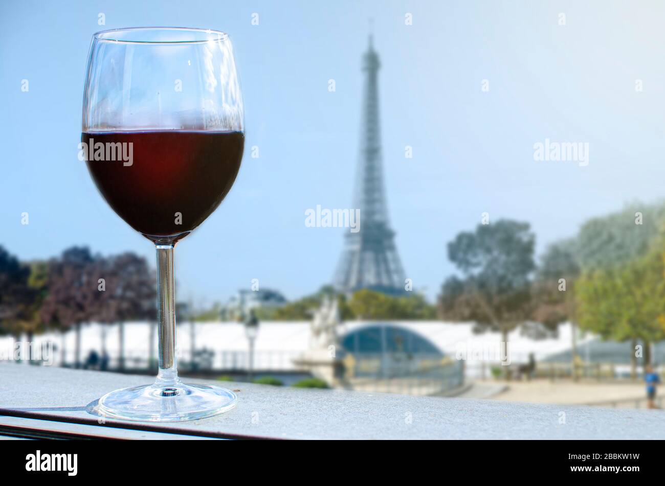 Glas Wein auf dem Eiffelturm verwischt den Hintergrund. Sonniger Blick auf das Glas Rotwein mit Blick auf den Eiffelturm in Paris, Frankreich Stockfoto