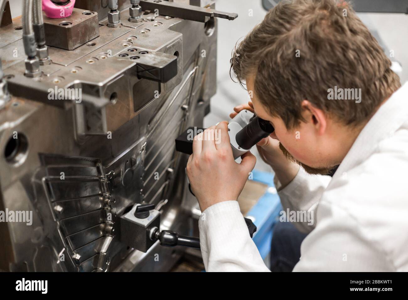 Qualitätsingenieur prüft Mängel an der Spritzform mit einem Mikroskop, Industriekonzept Stockfoto