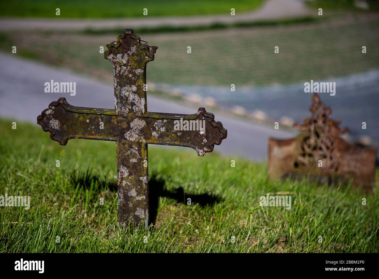 Altes, rostiges Kreuz in der Mitte des Feldes, mit Moos bedeckt Stockfoto