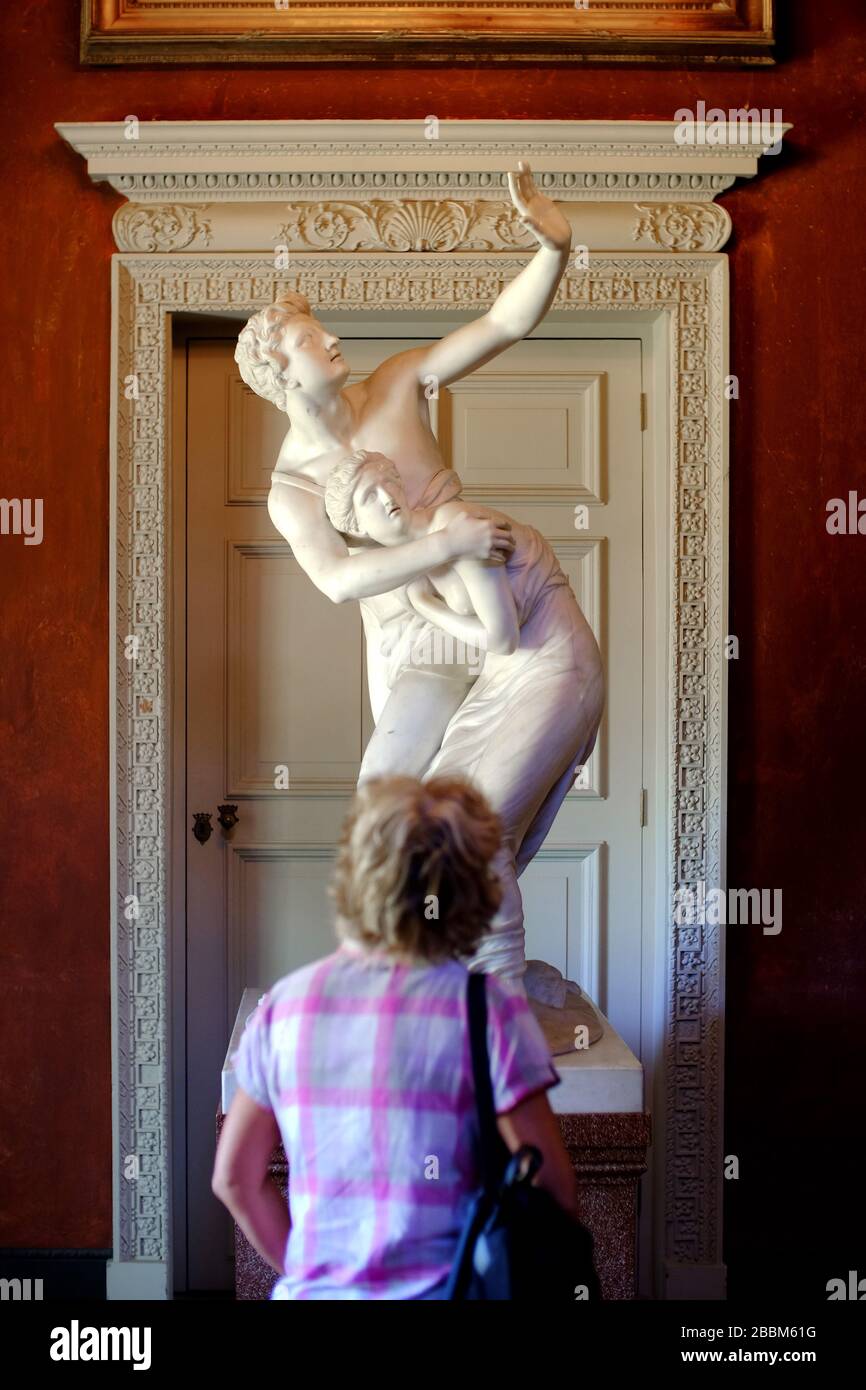 Frau, die eine klassische Marmorskulptur in einer Kunstgalerie/einem Museum mit traditionellen Geschlechterrollen betrachtet. Stockfoto