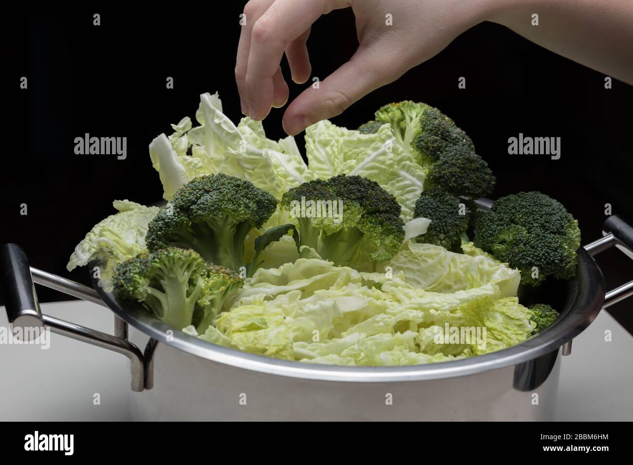 Frauen Hände halten Brokkoli und machen Low-Carb-Diät-Mahlzeit. Junge Hausfrau, die Rohkost vorbereitet. Stockfoto