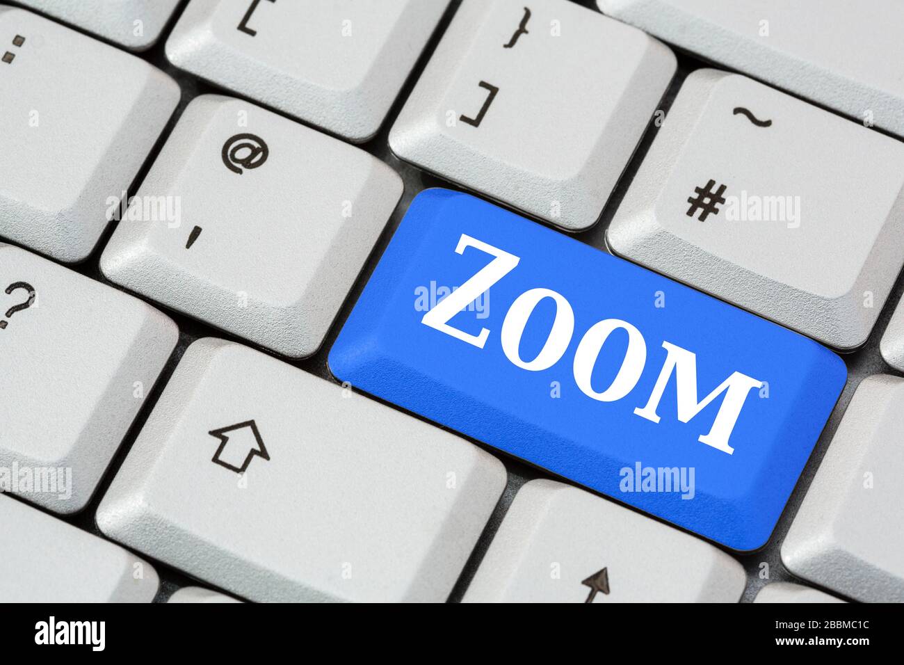 Eine Tastatur mit Zoom in weißer Schrift auf einer blauen ENTER-Taste. Zoom-App für Videokonferenz-Konzept. England, Großbritannien Stockfoto