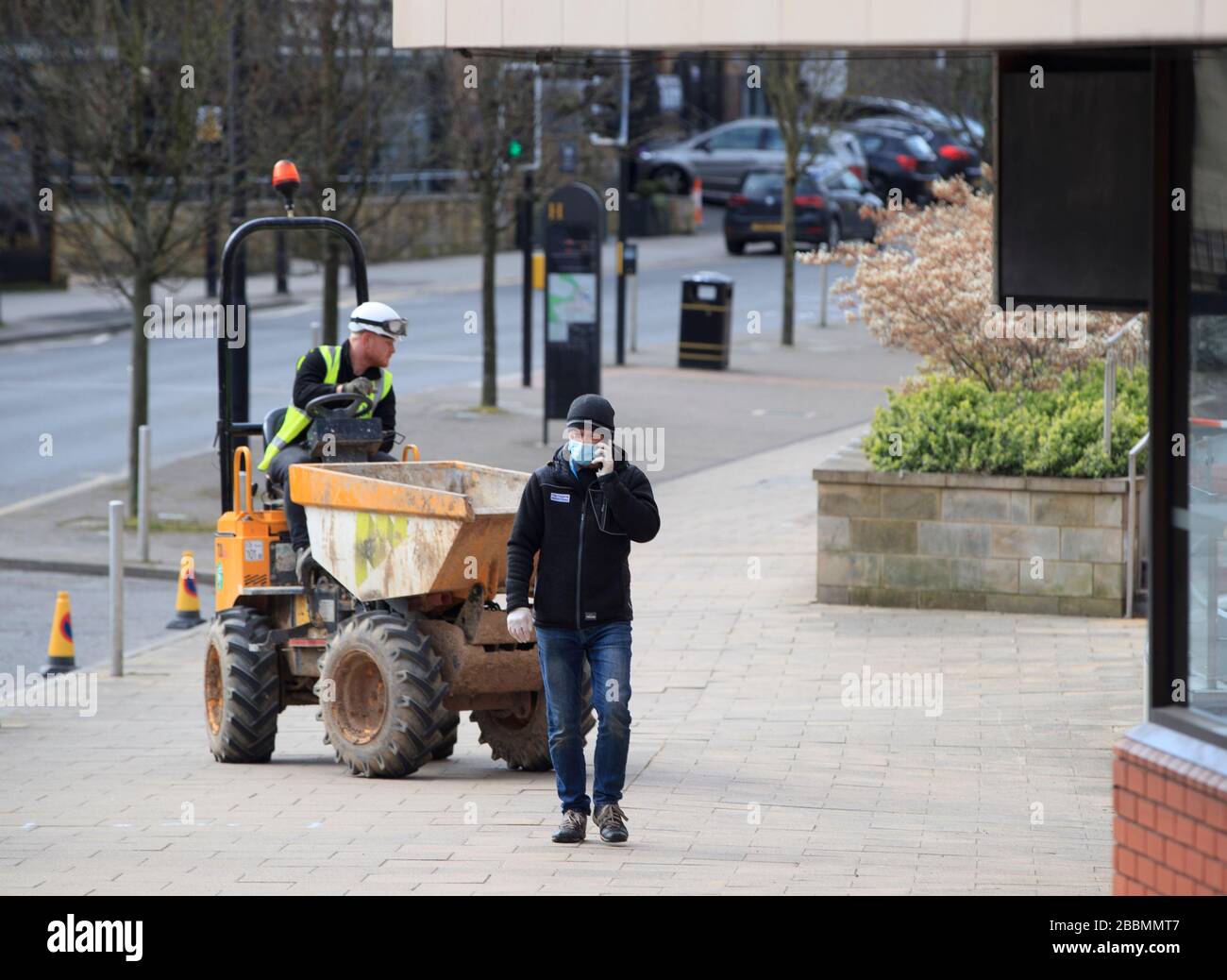 Ein Mann, der einen Facemask trägt, geht an einem Arbeiter im Harrogate Conference Center in Yorkshire vorbei, nachdem ein Abgeordneter gesagt hat, er sei ÒproudÓ, dass ein Konferenzzentrum von Harrogate im Kampf gegen Coronavirus offenbar als zeitweiliges Krankenhaus ausgewählt worden sei. Stockfoto