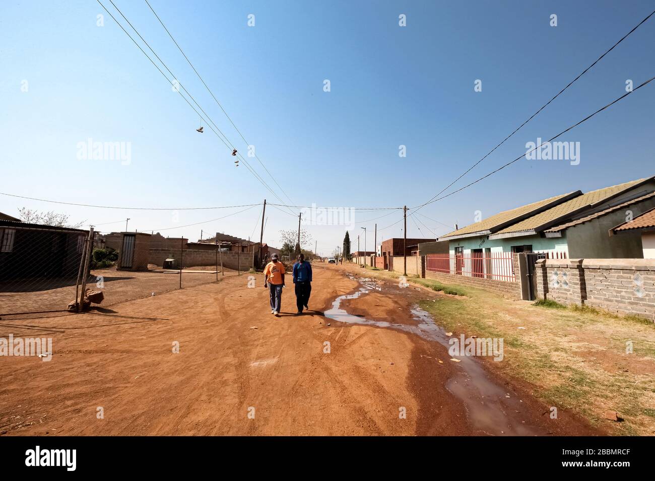 Soweto, Südafrika - 10. September 2011: Zwei afrikanische Männer, die auf einer Straße in der Nachbarschaft in den Vorstädten von Soweto spazieren gehen Stockfoto