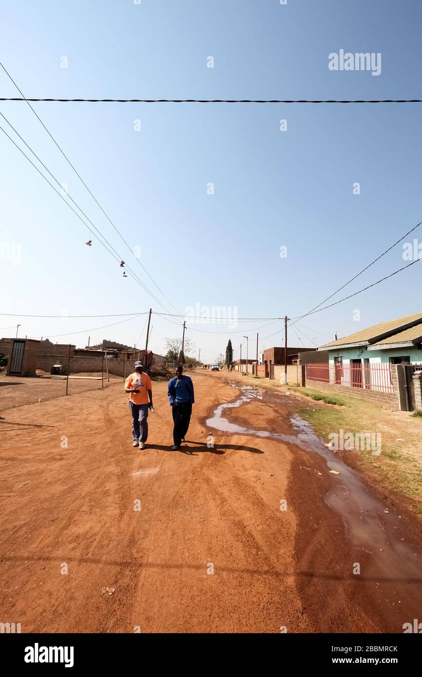 Soweto, Südafrika - 10. September 2011: Zwei afrikanische Männer, die auf einer Straße in der Nachbarschaft in den Vorstädten von Soweto spazieren gehen Stockfoto