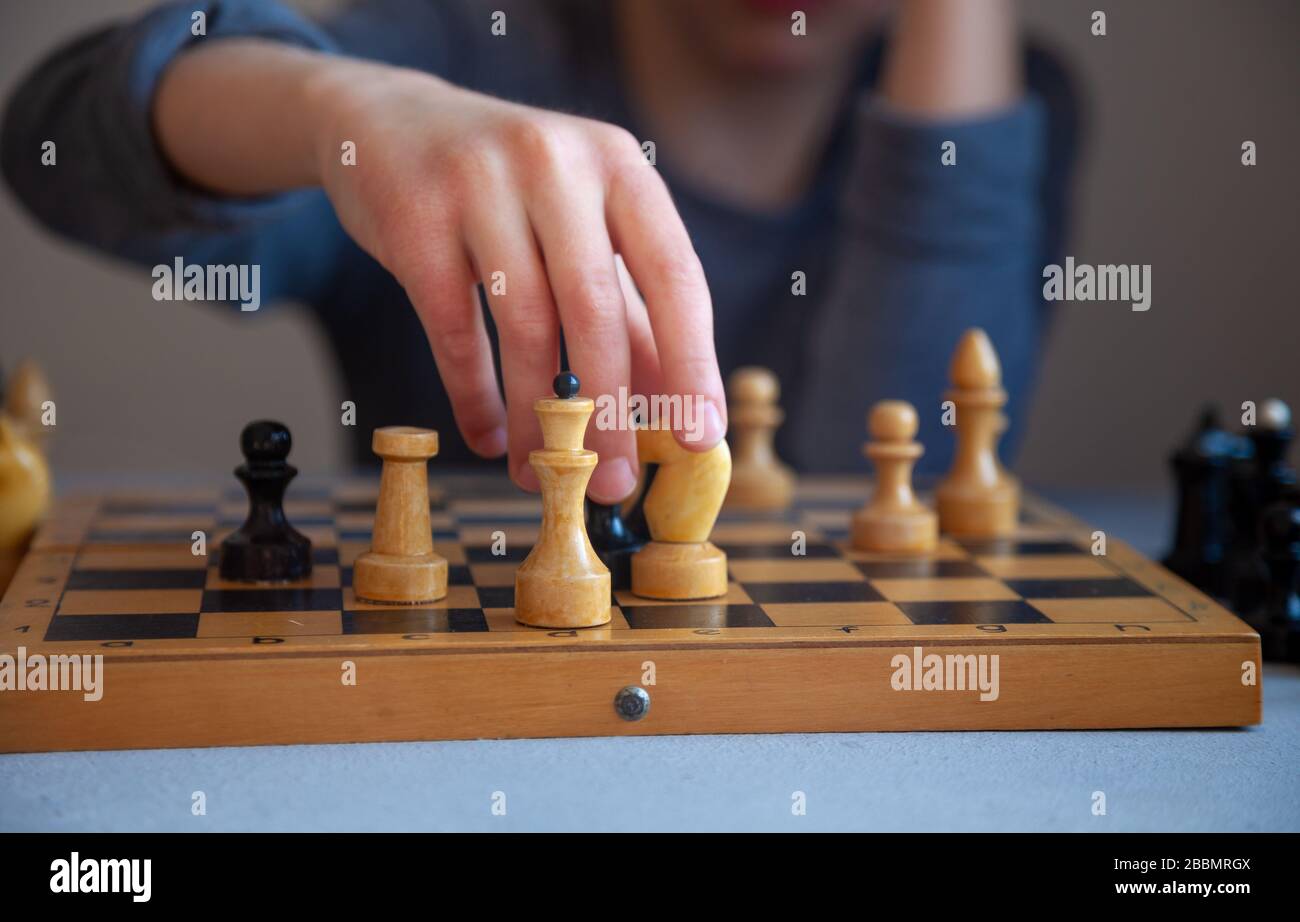 Ein Kind spielt allein Schach. Altes Holzkesselbrett. Kinderhände. Schachfiguren auf einem Schachbrett. Stockfoto