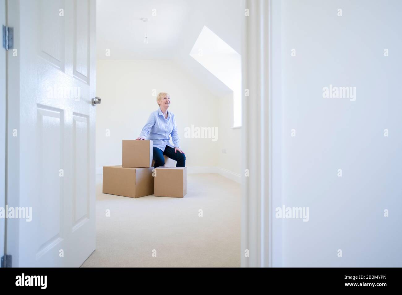 Seniorin Desizing In Ruhestand Sitzt Auf Boxen In New Home Am Beweglichen Tag Stockfoto