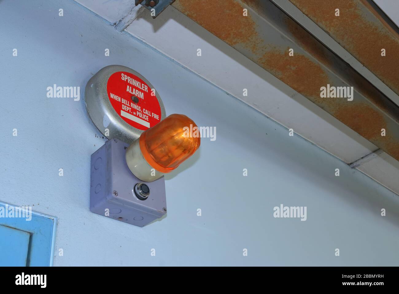 Wandsperrung der Sprinkleralarmglocke, die an der Wand über dem Türrahmen unter Elektrowire angebracht ist, Sicherheitskonzept Stockfoto