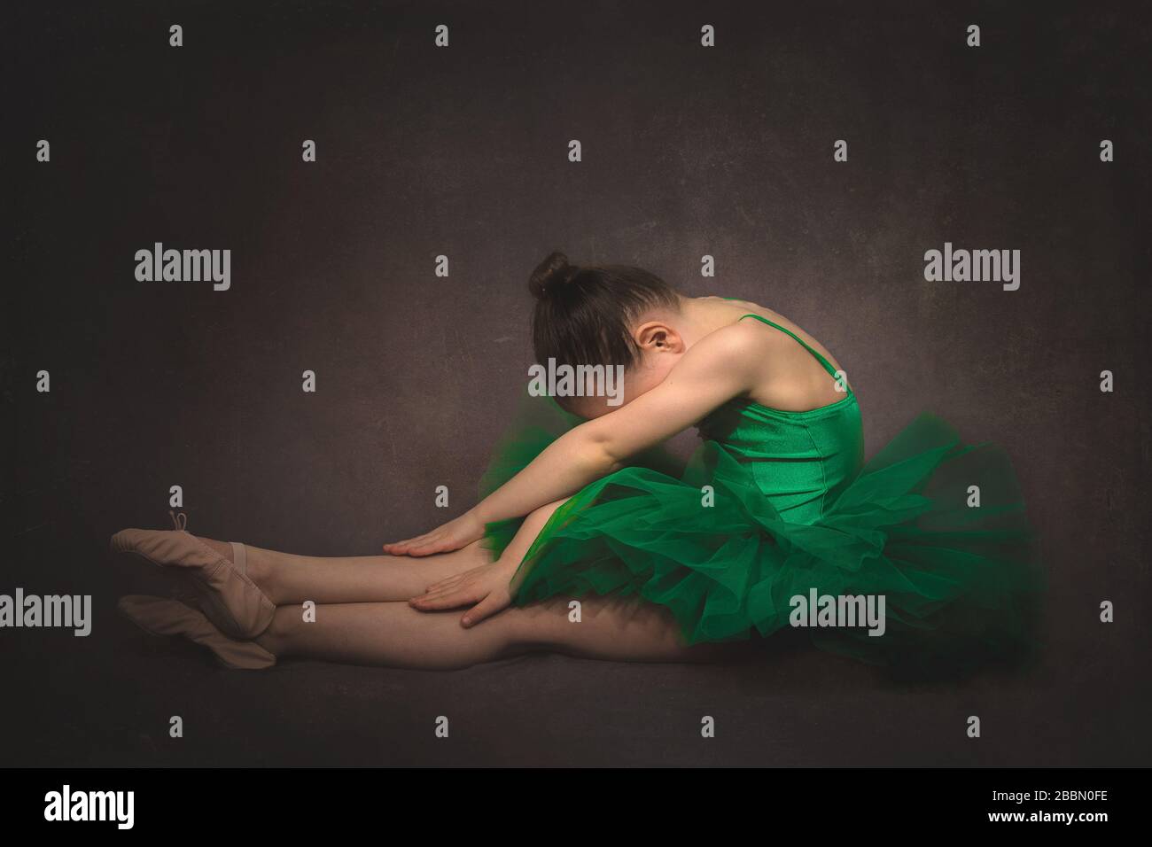 Junge Balletttänzerin in einem Studio mit grünem Tutu und braunem Hintergrund, Northamptonshire, England Stockfoto