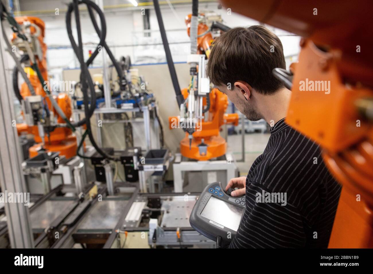 Junger Mann programmiert industriellen automatischen Roboter in der Automobilindustrie Stockfoto