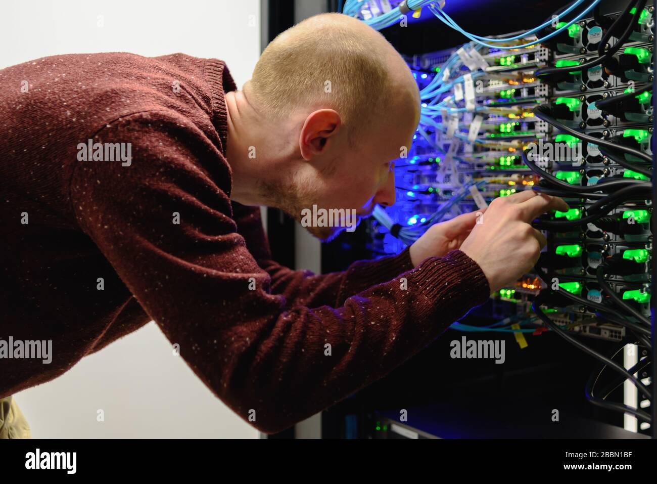 Man-Rechenzentrumstechniker, der Serverwartung durchführt. Ersetzen von Kabeln, Stockfoto
