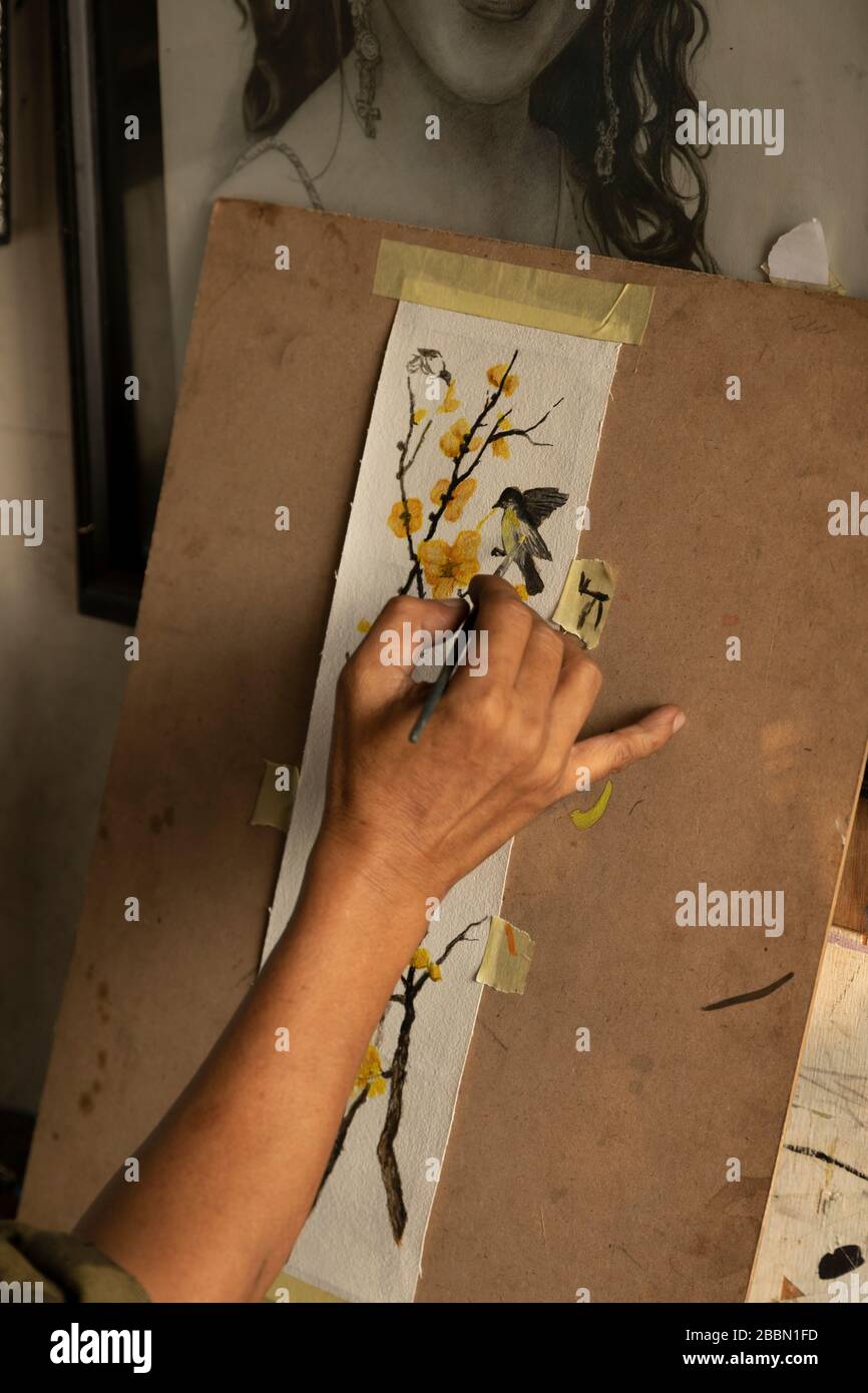 Jakarta, Indonesien - 13. Juli 2019: Ein lokaler Maler und Karikaturist malt in seinem kleinen Atelier einen blühenden Zweig mit Vögeln mit Acrylfarben. Stockfoto
