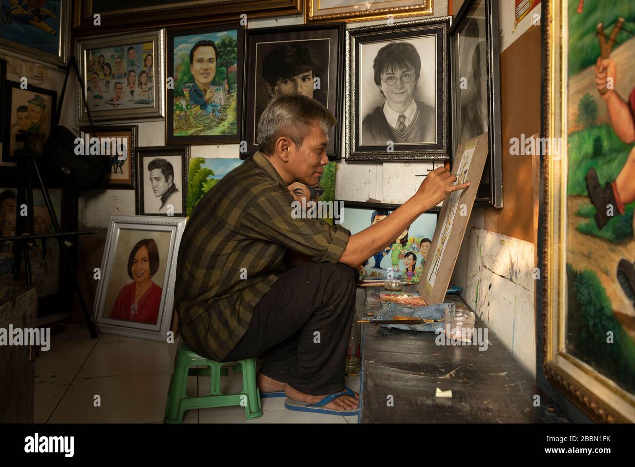 Jakarta, Indonesien - 13. Juli 2019: Ein lokaler Maler und Karikaturist malt in seinem kleinen Atelier einen blühenden Zweig mit Vögeln mit Acrylfarben. Stockfoto
