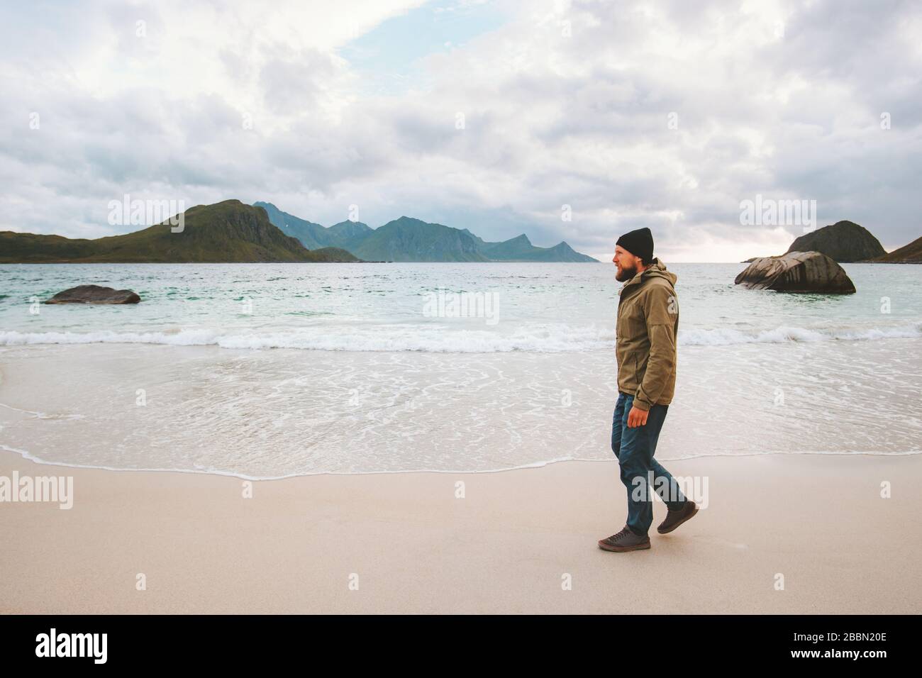 Man Tourist mit Blick auf das Meer am sandigen Haukland Strand unterwegs in Norwegen Aktivurlaub gesunde Lebensweise Lofoten Inseln im Freien Stockfoto