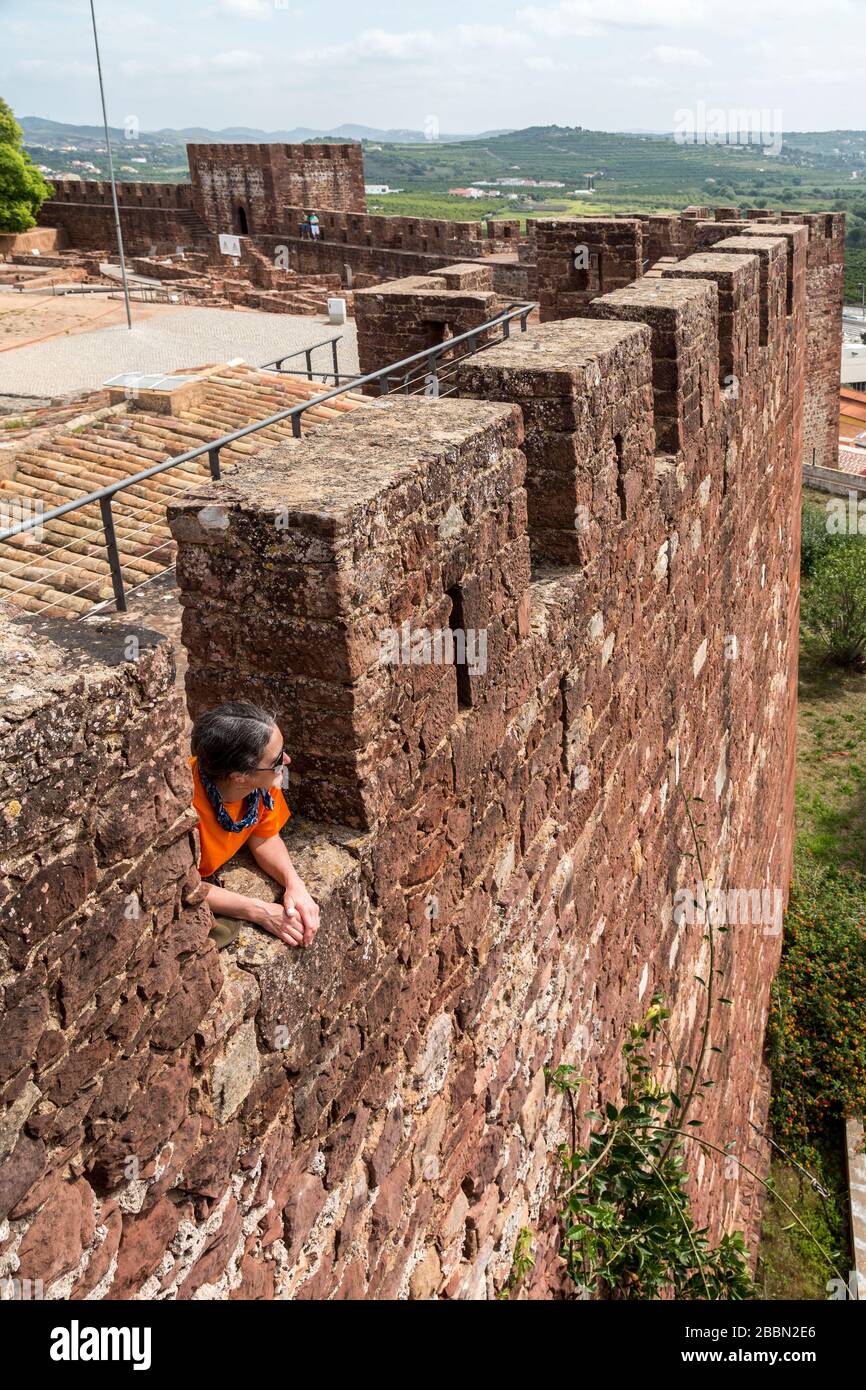 Person, die aus Zinnen auf der Burg an der Algarve, Portugal blickt Stockfoto