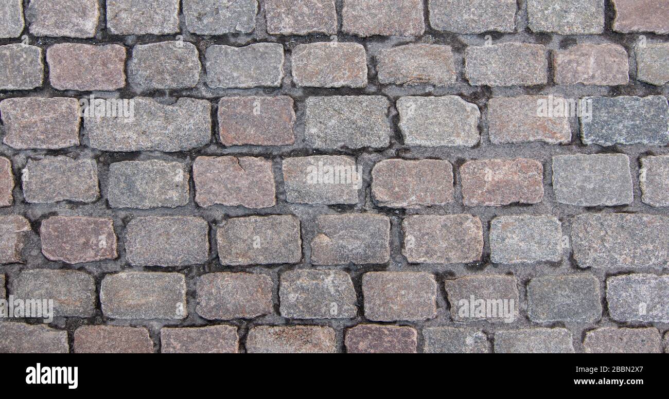 Altes Kopfsteinpflaster. Blick über die Decke von grauen rechteckigen Steinen. Hintergrundtextur, Nahaufnahme. Stockfoto