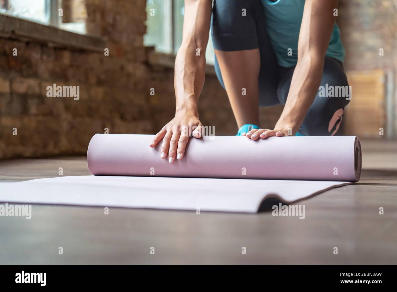 Sport Fit Frau Yogalehrerin trägt Sportswear Roll-Unroll-Yogamatte im Fitnessstudio. Stockfoto