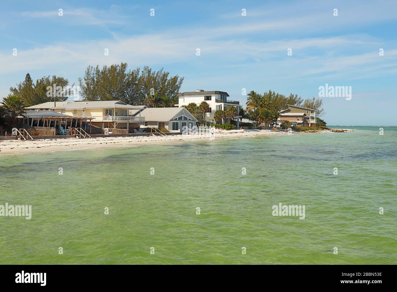 Skyline von Häusern am Strand am Bean Point am Nordende von Anna Maria Island, Florida, mit nicht erkennbaren Menschen, die auf dem Sand spazieren Stockfoto