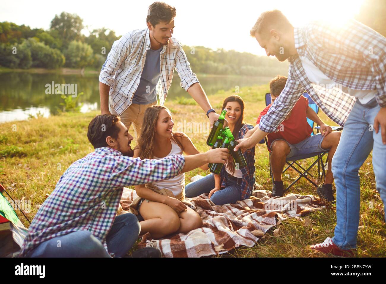 Junge Leute trinken, essen und stinken Gläser bei einem Picknick Stockfoto