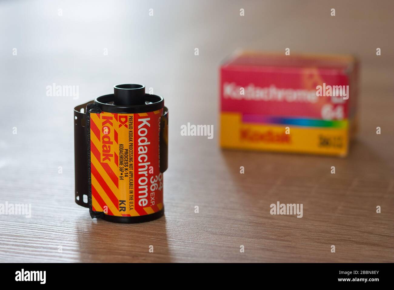 Rollen und Schachtel von Kodachrome 64, 35-mm-Dia-Film auf einem Tisch. Der bekannteste Transparenzfilm im 20. Jahrhundert. Fokus auf Vordergrund. Stockfoto