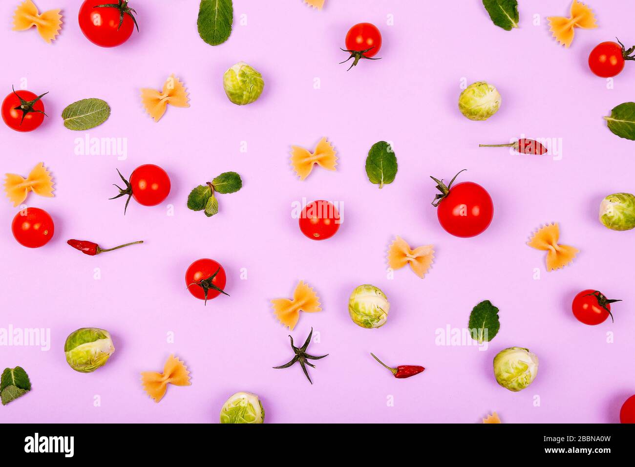 Bunte Nudelzutaten aus Kirschtomaten, brussel-spross, Farfalle und Pfeffer auf pinkfarbenem Hintergrund. Kochkonzept. Stockfoto