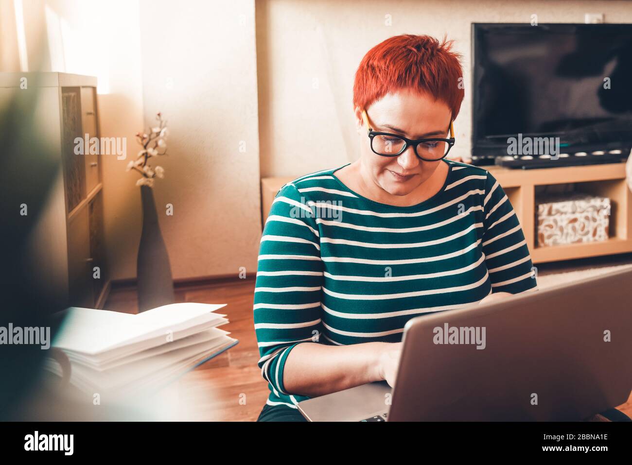 Junge Geschäftsfrau, die von zu Hause aus mit Laptop arbeitet. Heimbüro. Bleiben Sie zu Hause, studieren und arbeiten Sie online, isolieren Sie Coronavirus Stockfoto
