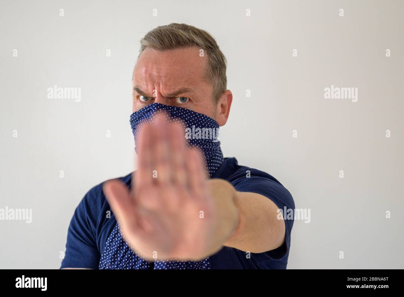 Mann, der einen Gesichtsschutz gegen Coronavirus oder Covid-19 trägt, der seine Hand hält, um soziale Distanzierungen durchzusetzen, um die Ausbreitung der Pandemie zu verhindern Stockfoto