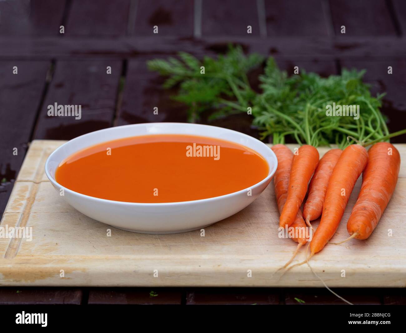Top-View-Winkel der hausgemachten Karottensuppe mit einem Haufen organischer Karotten auf dem Tisch Stockfoto