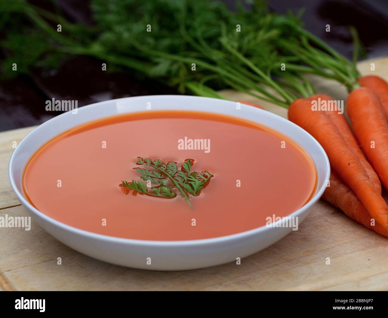 Top-View-Winkel der hausgemachten Karottensuppe mit einem Haufen organischer Karotten auf dem Tisch Stockfoto
