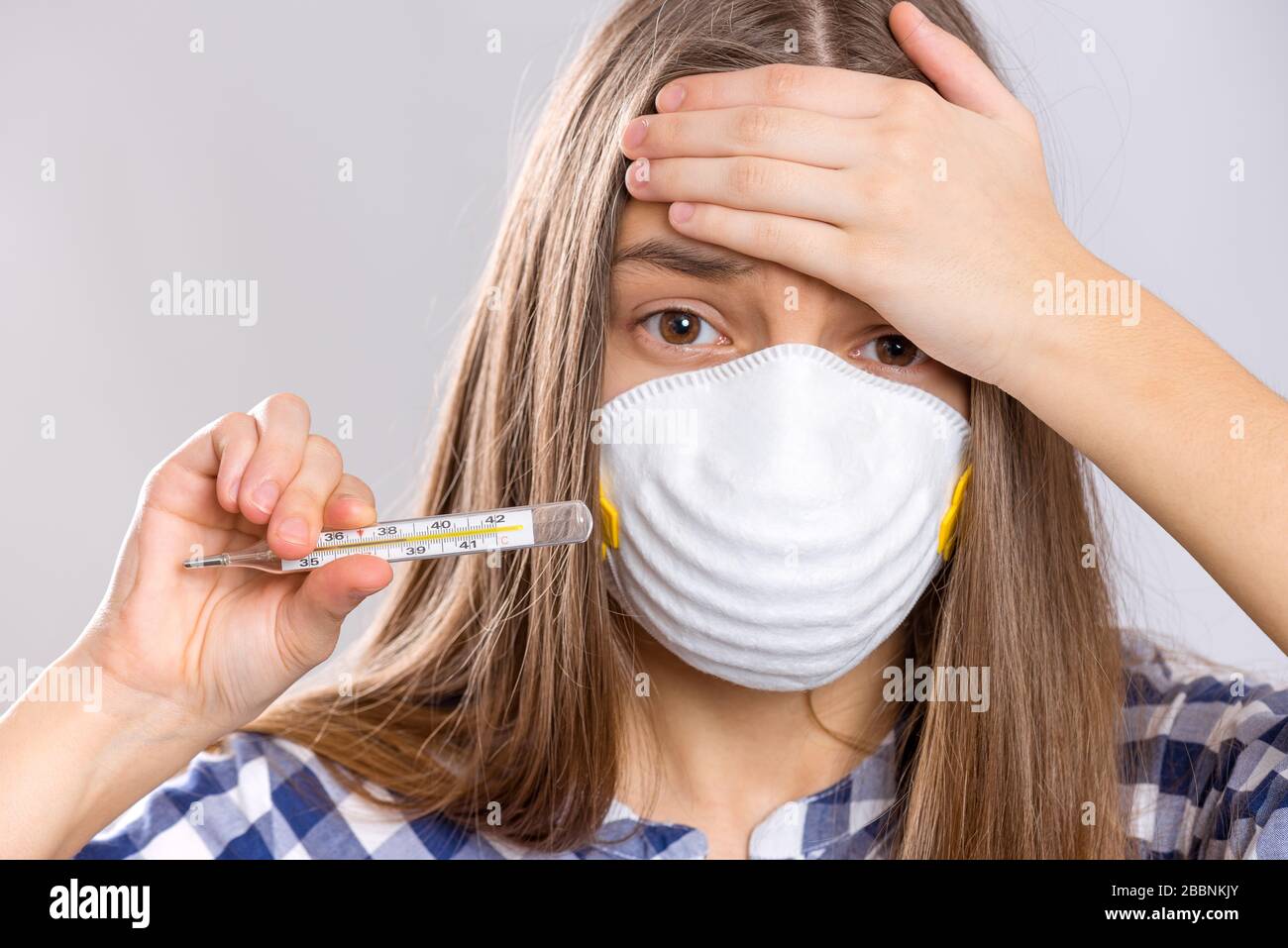 Konzept der Quarantäne von Coronavirus. SICK Child trägt eine medizinische Schutzmaske, die Thermometer mit hoher Temperatur hält. COVID-19 - Isolierung zu Hause. Sa Stockfoto