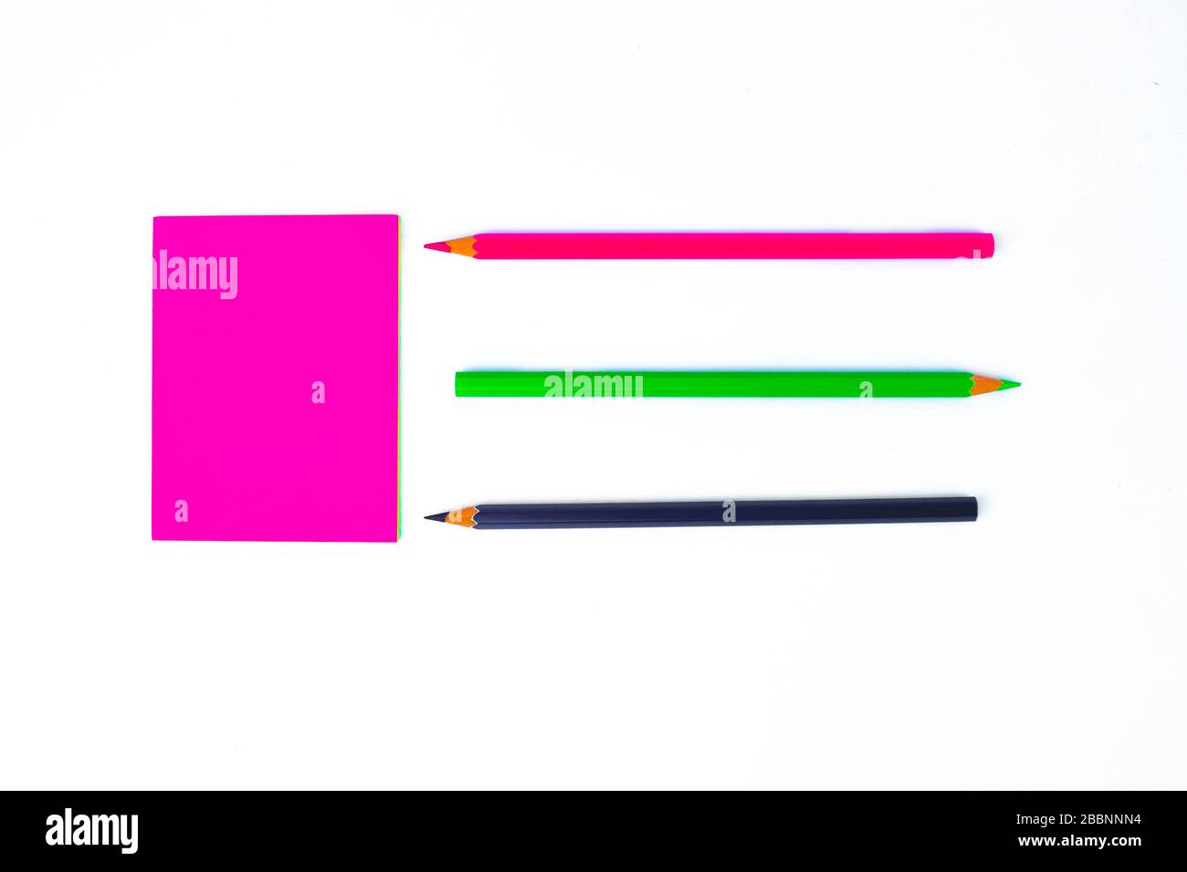 Draufsicht von drei verschiedenfarbigen Bleistiftkrebsen aus Holz, die auf eine pinke Haftnotiz zeigen Stockfoto