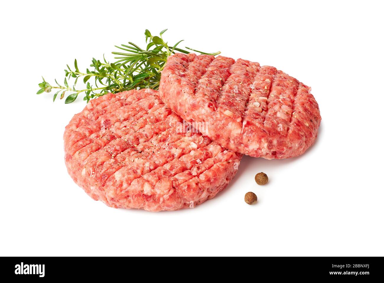 Zwei rohe Burger patties mit Thymian und Reosemary auf Weiß Stockfoto