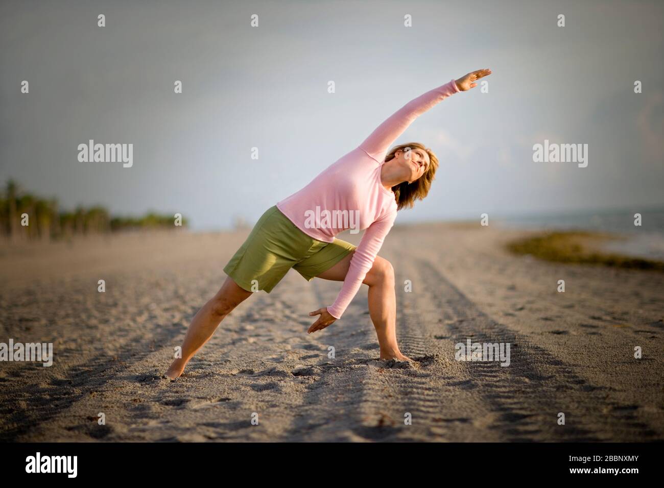 Mitte der erwachsenen Frau Yoga am Strand. Stockfoto