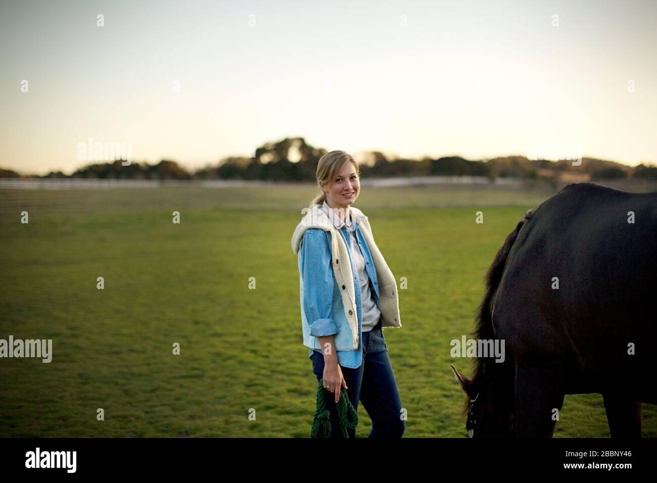 Porträt eines jungen Erwachsenen stehendes Mädchen mit einem Pferd in einem Feld. Stockfoto