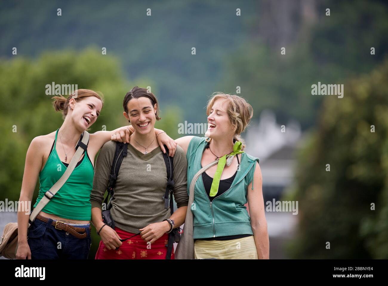 Drei lächelnde weibliche Touristen, die auf einer städtischen Straße spazieren. Stockfoto