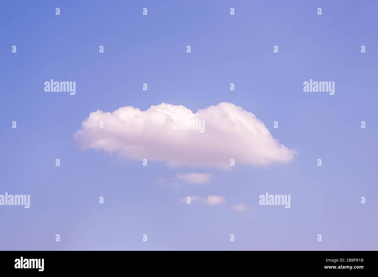 Blauer Himmel bei Sonnenschein mit einer großen weißen Wolke und mehreren kleinen weißen Wolken darunter wie Gedankenwolken oder Sprechblasen mit viel Kopienspachel Stockfoto