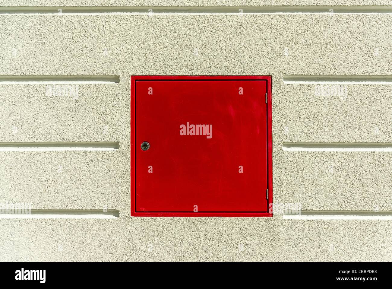 Detail der Fassade eines Wohnhausputzes mit horizontalen Gelenken und roter Wandhydrantenfeuerwehr Stockfoto