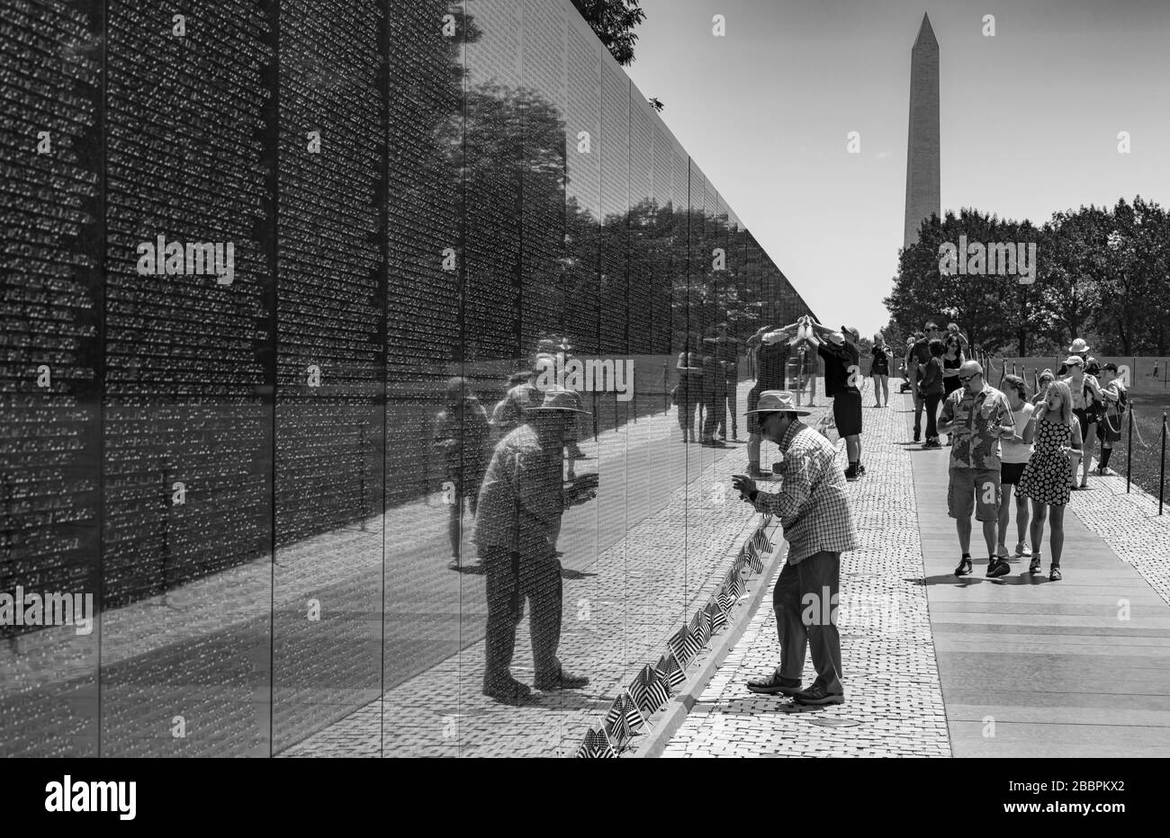 Freunde und Verwandte suchen auf dem polierten schwarzen Granit des Vietnam Veterans Memorial nach den Namen von Angehörigen, die im Krieg verloren gegangen sind. Stockfoto