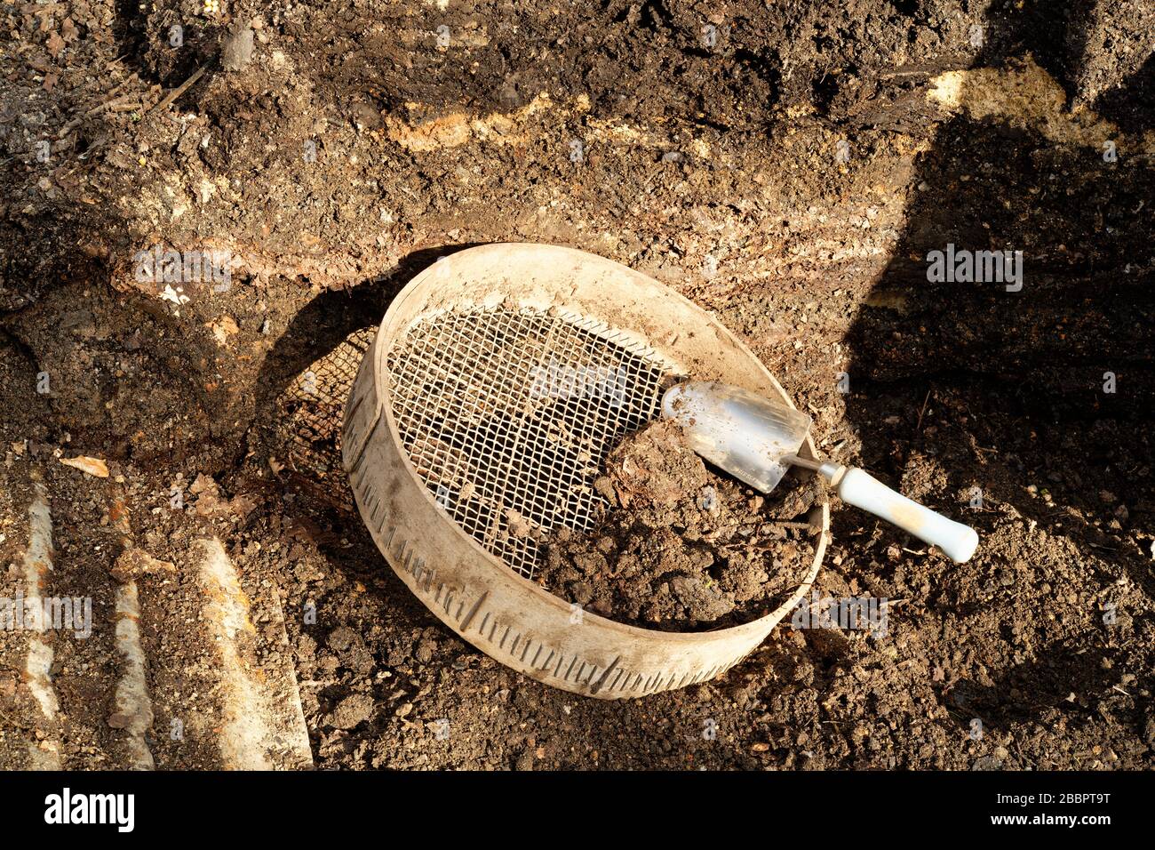 Ein Komposthaufen mit Bodensieb und kleinem Trowel. Stockfoto