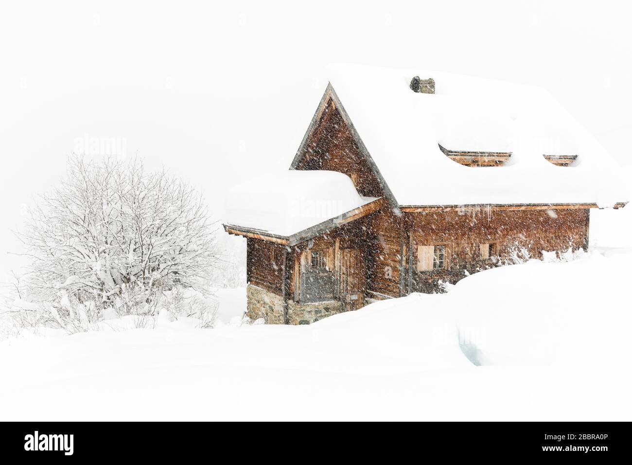 Starke Witterung, Schneefall, extreme weiße Landschaft mit Holzhaus und Baum bedeckt mit viel Schnee Stockfoto