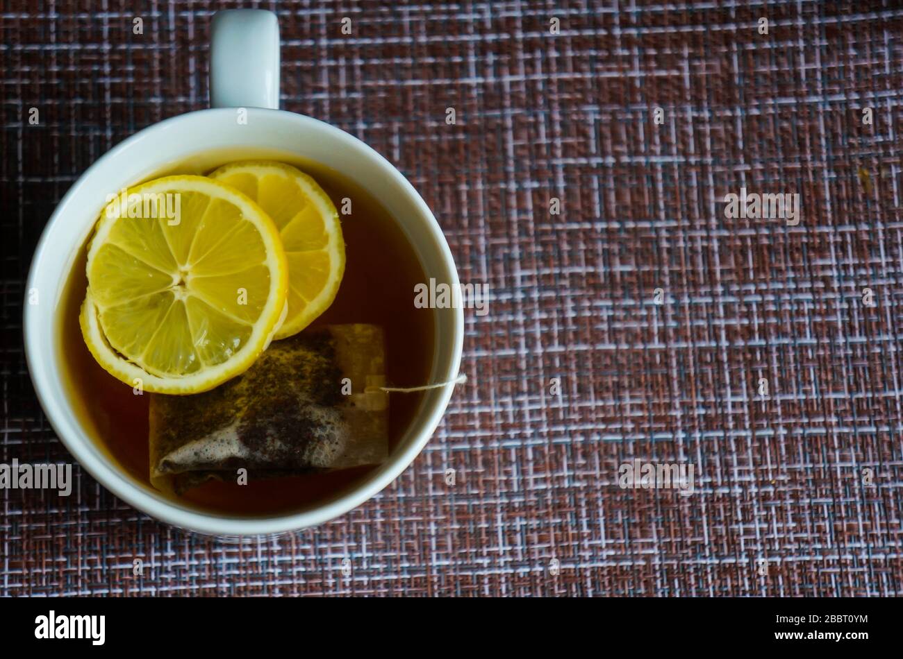 Eine Tasse schwarzen, kräftigen Tees mit Zitrone- und Teetasche, gegen den Virus und die übliche Kälte Stockfoto