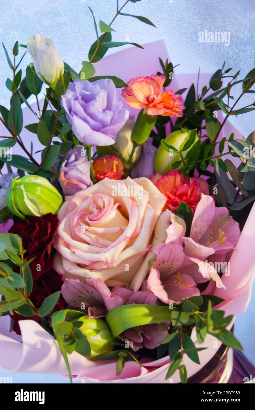 Feiner Blumenstrauß aus verschiedenen Blumen in rosafarbener Verpackung. Nahaufnahme des vertikalen Fotos. Stockfoto